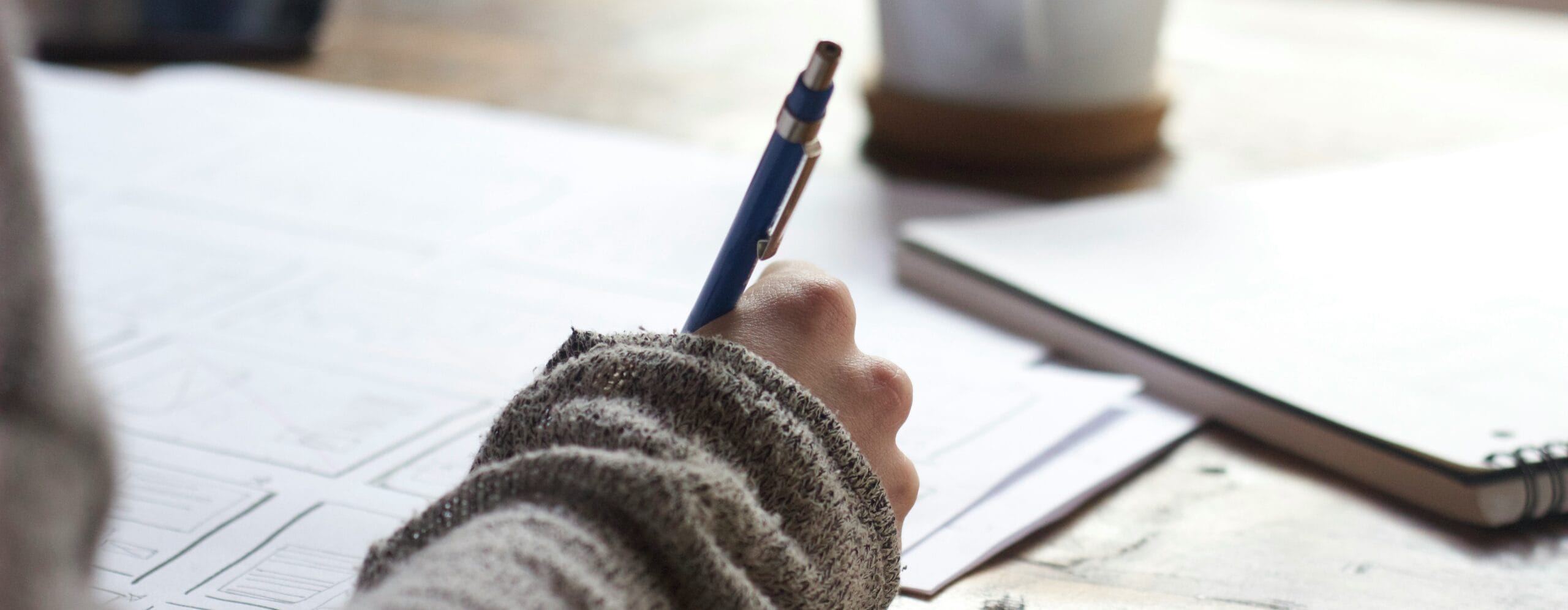 Hand holding a pen while wring on a paper.